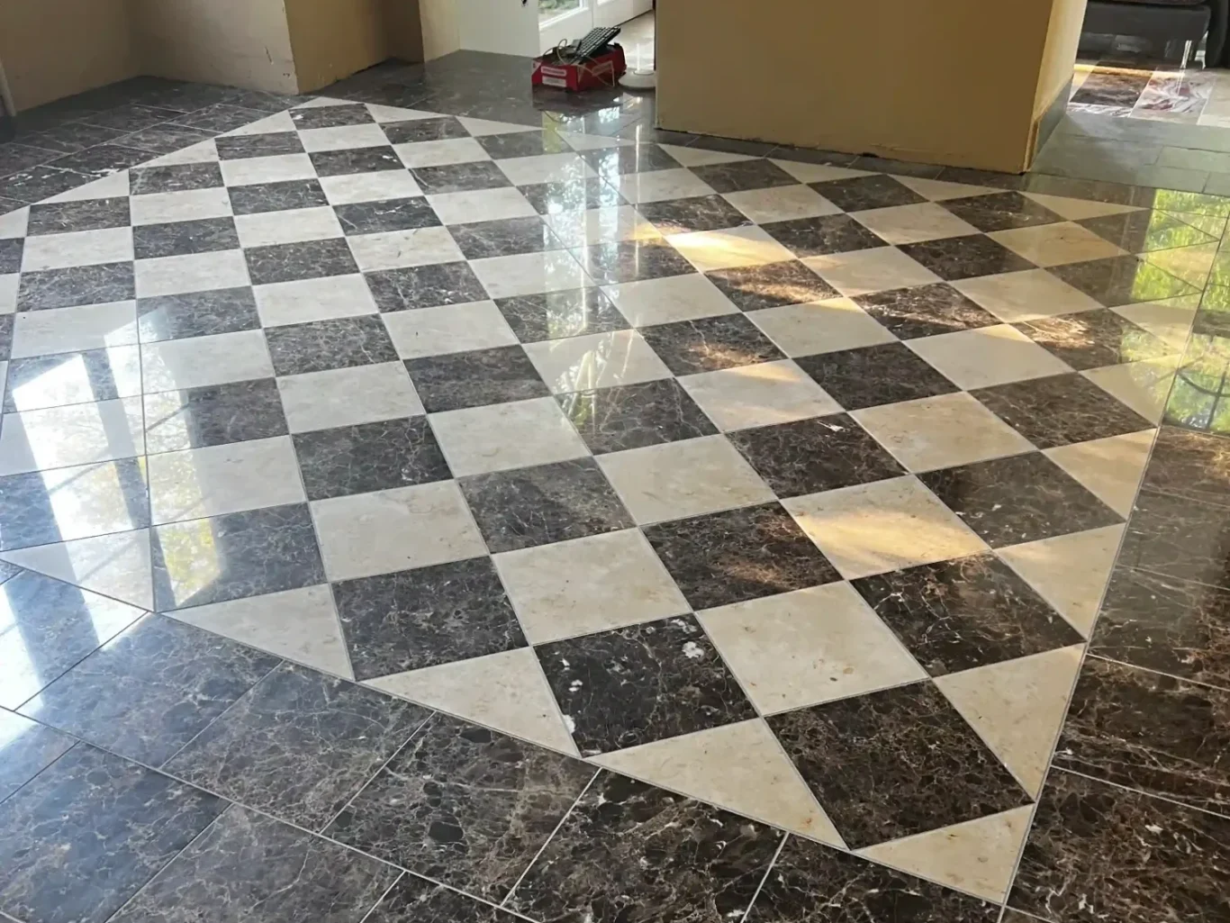 Naturstein Boden mit schwarz-weißen Schachbrettmuster und reflektierendem Finish.